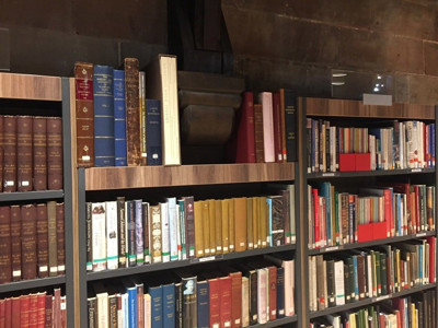 Wooden shelving filled with a variety of books, including leather-bound volumes and colourful spines, at Lichfield Local Studies