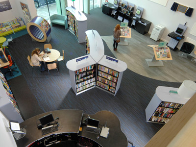 Curved browsing shelves and study tables in a children's reading area at Thame Library