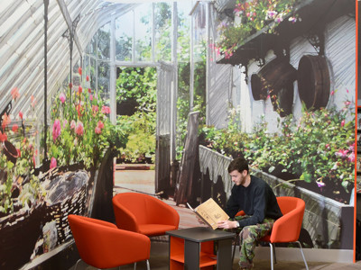Orange lounge chairs surrounding a study table with a student reading at Brackenhurst Campus Library