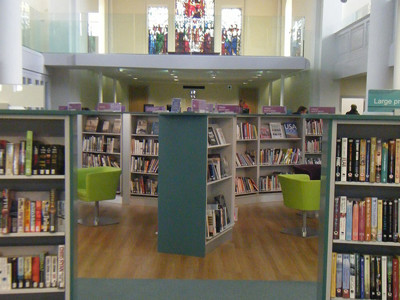 Green lounge chairs beside browsing shelves in an open-plan library space at St Aubyn Library Church