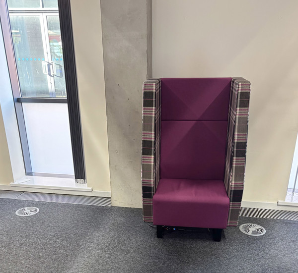 Purple upholstered high-back chair with plaid detailing in a quiet reading space at Oldham Library
