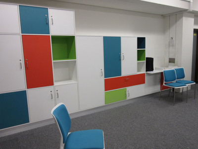 Bright blue and green storage units with white cabinetry and a study table at County Library Oxfordshire