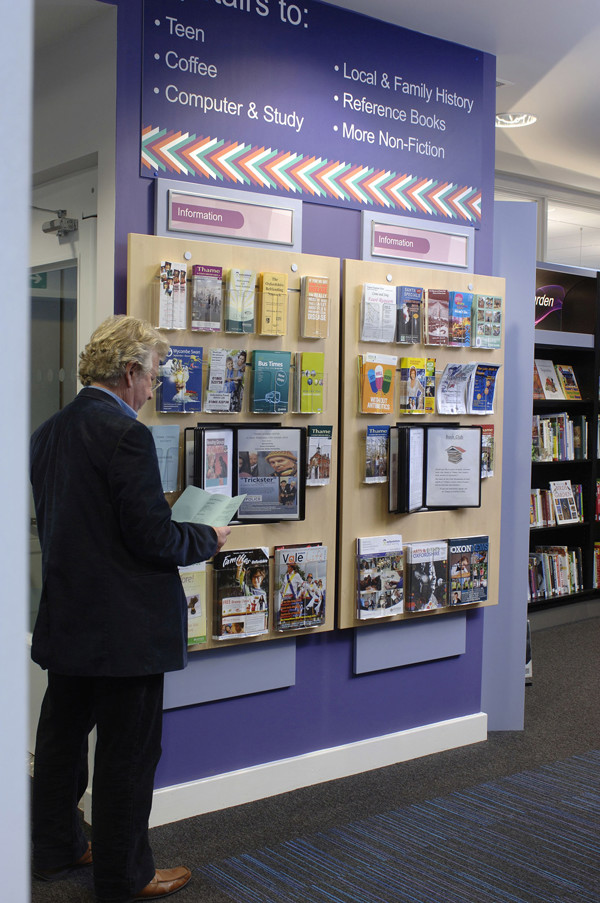 A patron browsing a well-organised leaflet display featuring various informational brochures at Thame Library