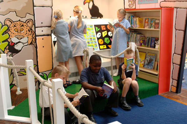 Children engaged in book browsing at a colourful reading nook with playful wall graphics at Wentworth Primary School