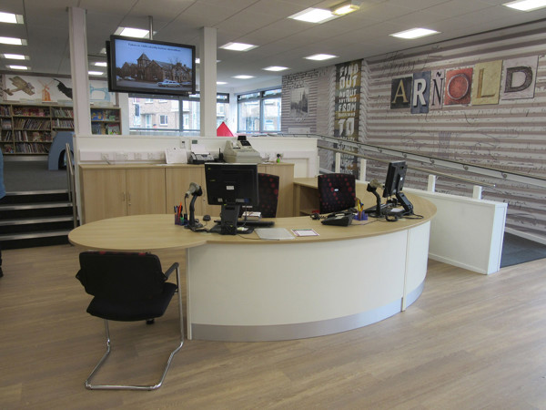Curved help desk with dual computer stations and a television screen at Arnold Library