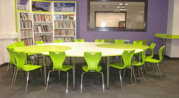 Circular white study table surrounded by green chairs in a collaborative work area at Werneth School Library