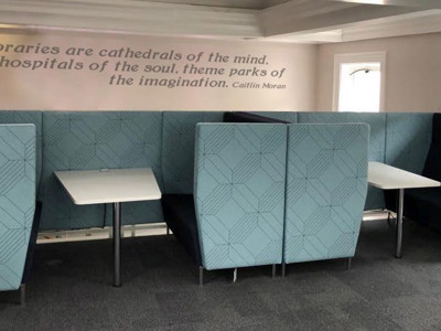 Blue upholstered booths with white tables in a collaborative work area at Clapton Library