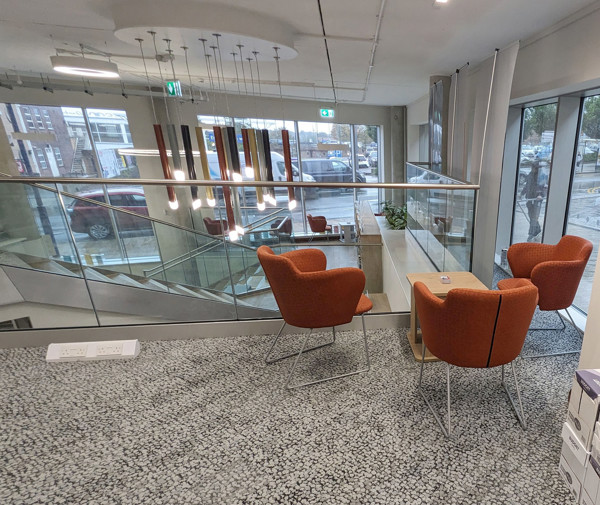 Orange lounge chairs beside a wooden side table in a light-filled reading lounge at City Central Library Stoke On Trent