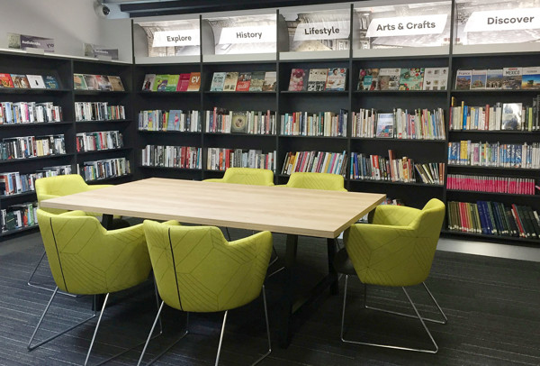 Lime green upholstered chairs around a large wooden table in a study area at Aireborough Library