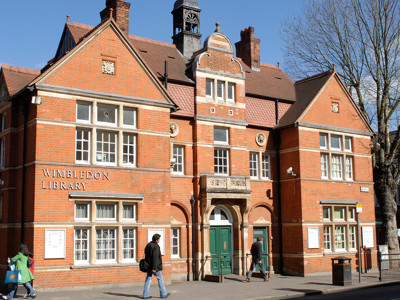 Red brick façade with ornate architectural details and a clock tower at Wimbledon Library