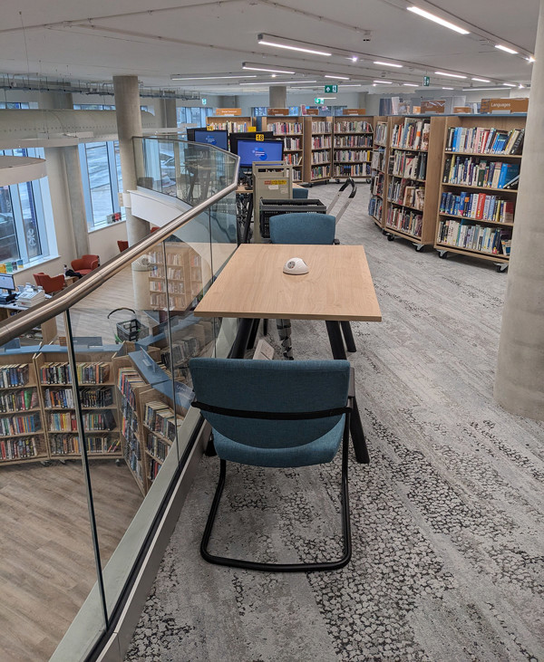 Light blue study chairs and a wooden table overlooking browsing shelves in a quiet reading space at City Central Library Stoke On Trent