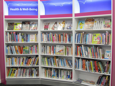Curved shelving filled with health and wellbeing books in a dedicated browsing area at South Woodford Library