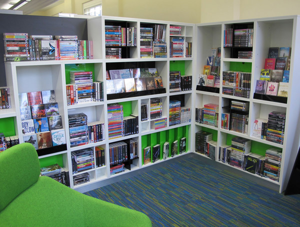 Green upholstered seating beside brightly coloured shelving filled with books and DVDs at West Bridgford Library
